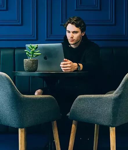 Stock photo of a young man sitting at a laptop in a cafe.